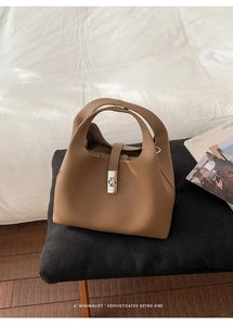 Top view of a brown pebbled leather bucket bag on a grey bench with minimalist retro style