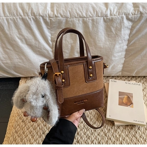 Détail du sac seau vintage bicolore en cuir avec charm lapin en peluche et bandoulière chic