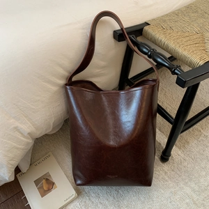 Detailed view of deep brown faux leather tote bag with vintage oil-wax texture on a chair