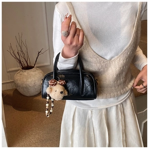 Détail d'un mini sac bowling noir avec breloque ours en peluche et chaîne perlée