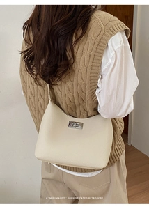 Detailed view of cream leather shoulder bag with silver metal twist lock on model