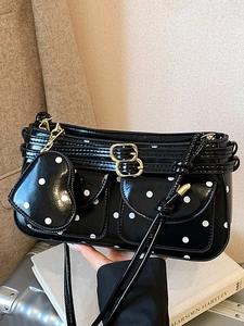 Polka dot black patent leather handbag with front pockets and heart-shaped charm accessory
