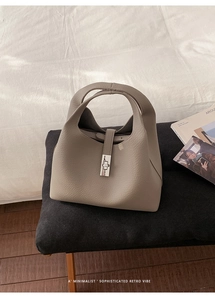 Detail of grey lychee leather bucket bag with silver metal padlock and dual handles
