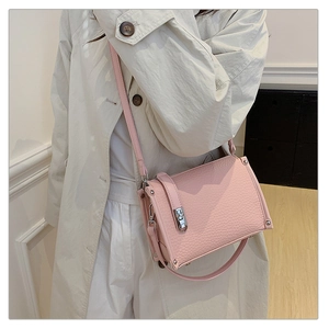 Close-up of pink litchi grain leather crossbody bag with silver hardware and rivets