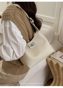 Detailed view of beige lychee leather hobo bag with a silver rotating lock on a shoulder strap