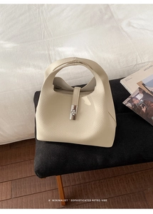 Detail of the creamy white lychee grain leather texture and silver metal twist lock