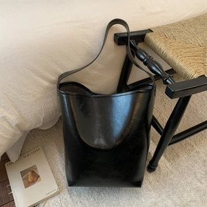 Detail showing the glossy black bucket bag on a chair in a lifestyle setting