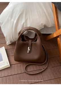 Detailed macro view of brown lychee grain leather bucket bag with silver lock closure