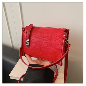 Close-up of red lychee grain leather handbag with silver metallic rivets and hardware