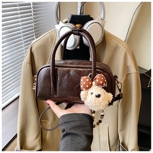 Détail du sac bowling rétro en cuir marron avec breloque ours en peluche et chaîne de perles