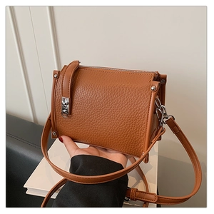 Close-up of brown litchi pattern leather crossbody bag with silver zipper and rivets
