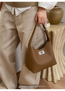 Detail of a brown lychee pattern leather handbag with a sleek silver metal turn-lock buckle