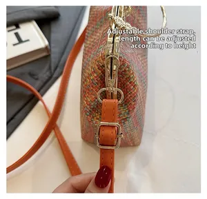 Détail de la bandoulière réglable en cuir orange avec boucle en métal doré du sac tissé