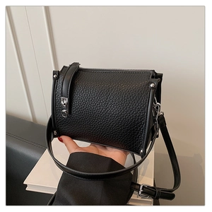 Close-up of black lychee grain leather square bag with silver metal zipper and shoulder strap