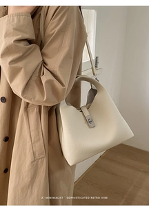 Detailed close-up of beige lychee grain leather bucket bag with silver metal swivel lock