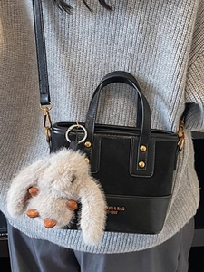 Sac seau rétro noir en cuir avec rivets métalliques et breloque lapin en peluche sur mannequin