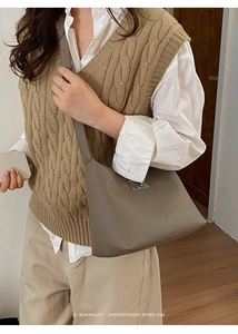Detail showing taupe leather shoulder bag with silver metallic buckle on model outfit