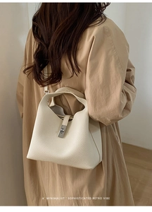 Detail of beige lychee leather bucket bag showing metal lock and fine stitching