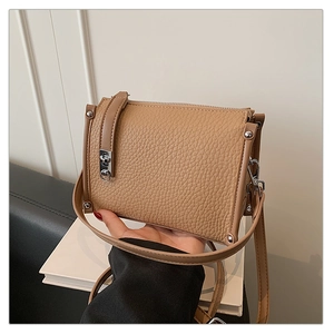 Close-up of khaki litchi grain leather texture with silver rivets and metal hardware