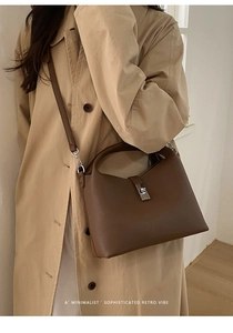 Close-up of dark brown lychee grain leather bucket bag with silver twist lock and handle