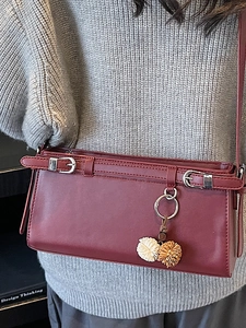 Vintage reddish-brown leather crossbody bag with silver buckles and pompom charm for women