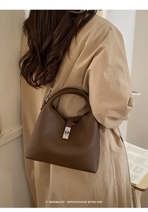 Detail of deep brown lychee grain leather texture and vintage metal twist lock on a bucket bag