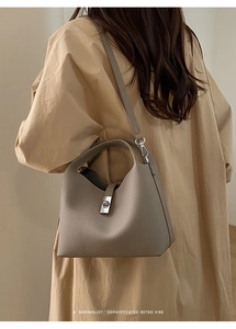 Detail of grey pebble leather bucket bag featuring a sleek silver twist lock closure