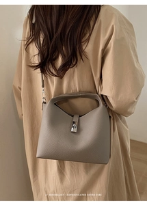 Detail showing the lychee grain leather texture and silver twist lock on the bucket bag