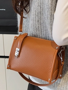 Elegant brown pebble grain square crossbody bag with silver buckle worn by a model