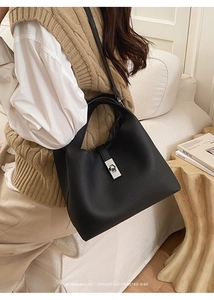 Detail of black lychee grain leather bucket bag with silver metal twist lock and strap