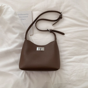 Detail of dark brown lychee leather texture and silver metal rotating lock on shoulder bag