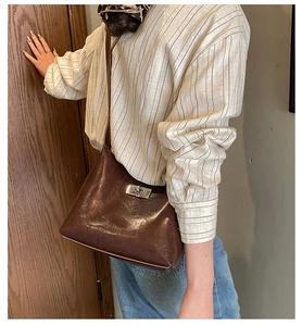 Detail view of a vintage dark brown oil-wax leather shoulder bag with a silver metal turn-lock