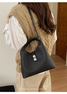 Detail of minimalist black pebbled leather handbag with silver metallic rotating clasp