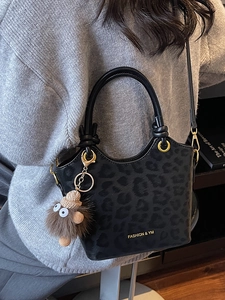 Borsa a secchiello minimalista nera leopardata con scritte dorate e ciondolo in peluche