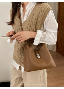 Detail of brown litchi grain leather bucket bag with silver twist lock and strap