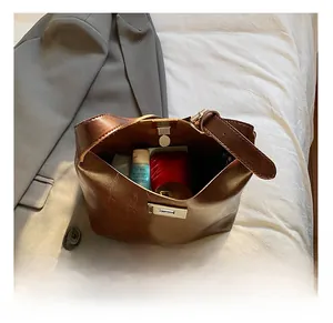 Interior capacity view of brown leather bucket bag showing skincare items and metal clasp