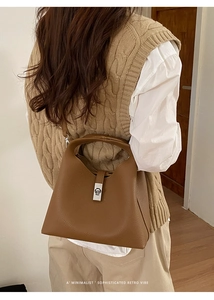Detail of minimalist brown pebble leather bucket bag with silver twist-lock and handle