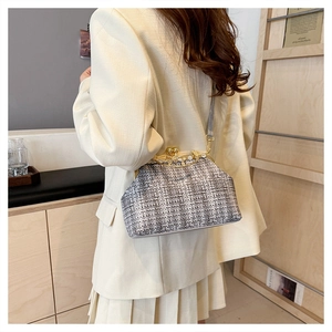 Détail d'un sac à fermoir kiss-lock en tweed gris porté par un mannequin en studio