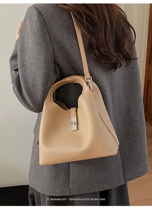 Model wearing a retro beige leather bucket bag with silver clasp and shoulder strap