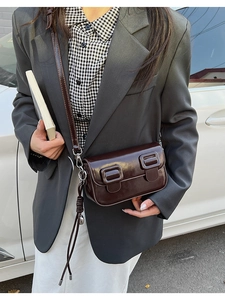 Detail of a dark brown glossy leather baguette bag with dual square buckle accents