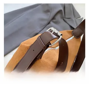Détail d'une bandoulière réglable en cuir marron avec boucle sur sac en daim chic