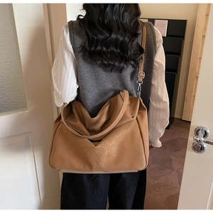 Detailed view of brown suede tote bag with floral embossing shown on model shoulder