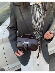 Detail view of deep brown glossy leather handbag with silver H-shaped metal buckle closure