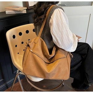 Detail of a brown leather tote bag featuring 3D floral embossing and a wide shoulder strap