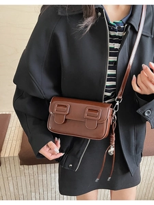 Brown retro leather saddle bag detail with woven tassel and twin buckle flap design