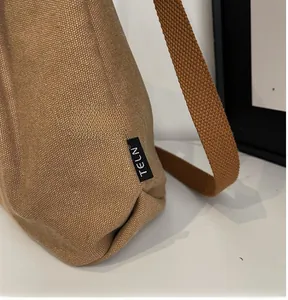 Detail view of the brown canvas tote bag with side woven label and thick strap