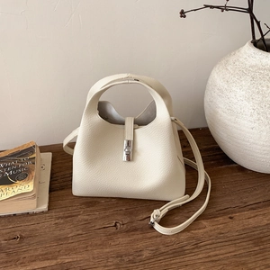 Close-up of cream leather bucket bag showing litchi texture and silver metal lock