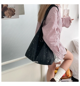 Detail of large black felt Hobo bag with white star pattern worn as a shoulder bag