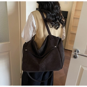 Detail of dark brown tote bag featuring matte texture and embossed front patterns