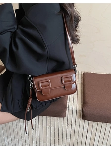 Detail view of a vintage dark brown saddle bag with stylish long tassels on side